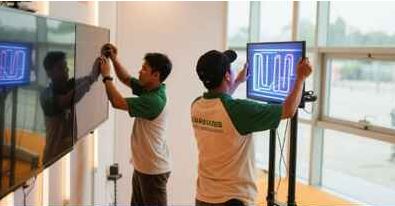 Teknisi memasang TV LED pada acara corporate profesional di Jakarta Timur